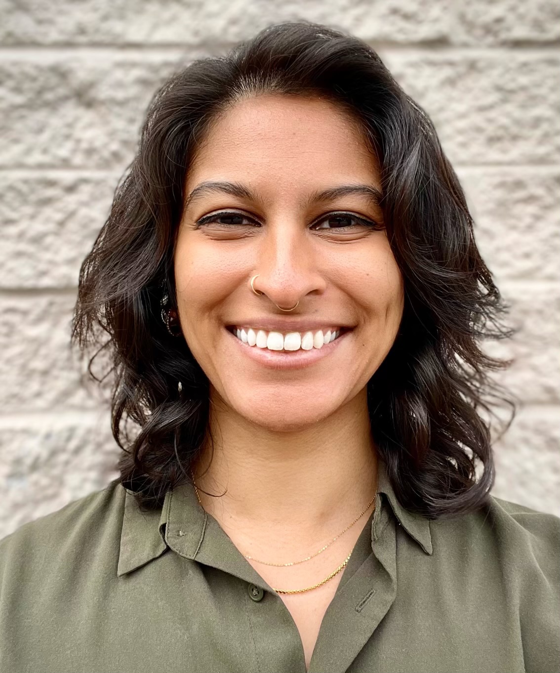 East-asian woman smiling at camera against brick wall